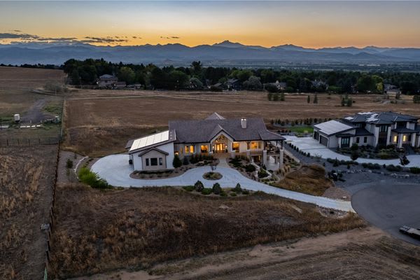 twilight drone photo of house with lights on and mountains in the background